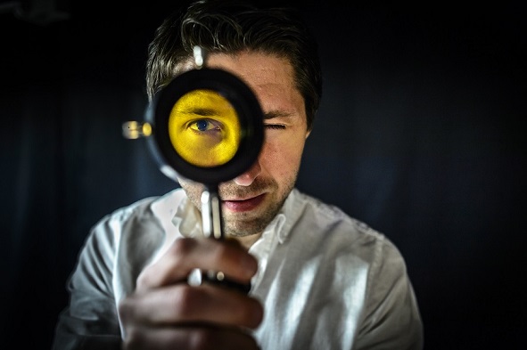 Researcher looking through a yellow lens. Photo.