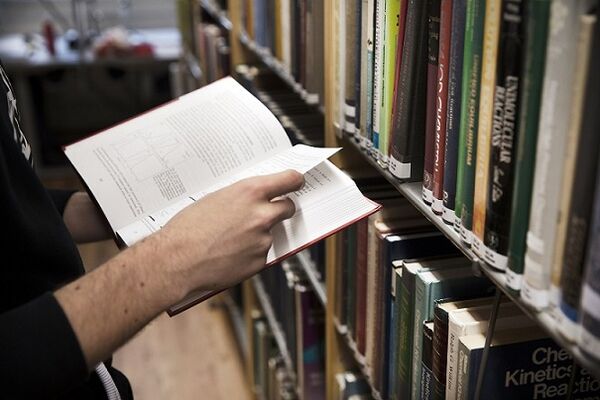 Händer som håller en bok. Foto.