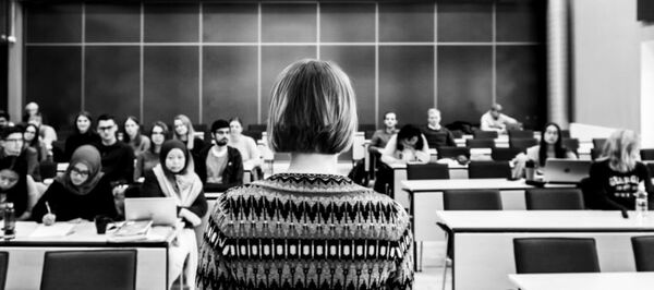 Teacher in fron of students in a lecture hall. Photo.