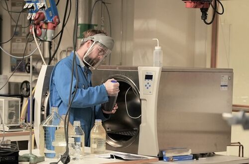 Forskare håller en flaska med kemikalier i ett laboratorium. Foto.