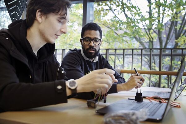 Two students talking and looking at computer. Photo.