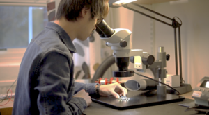 Researcher Siyu Tan observing a CMOS chip in EIT lab using a microscope.