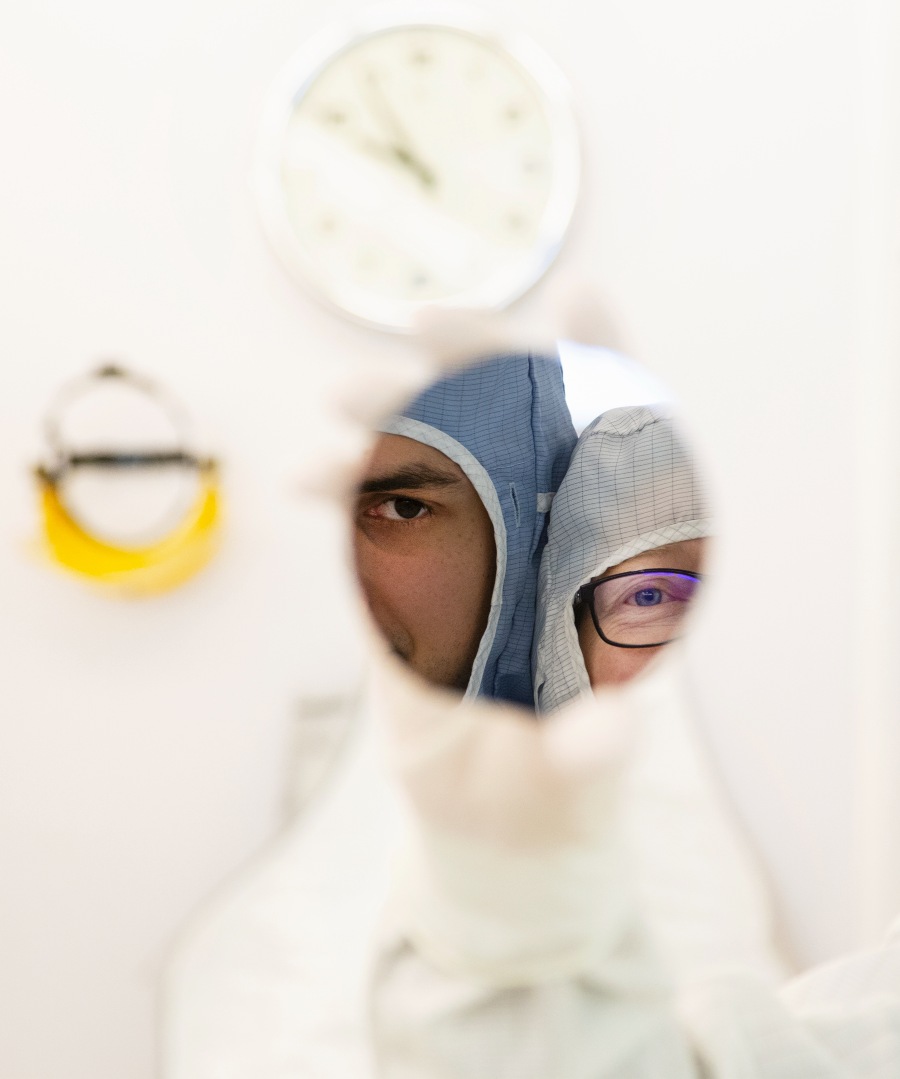 Two persons looking in the camera through a round window. Photo.