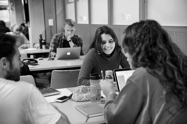 En grupp studenter pluggar på LTH:s Studiecentrum. På bordet framför sig har de en laptop, vattenflaskor och anteckningsblock. Foto.