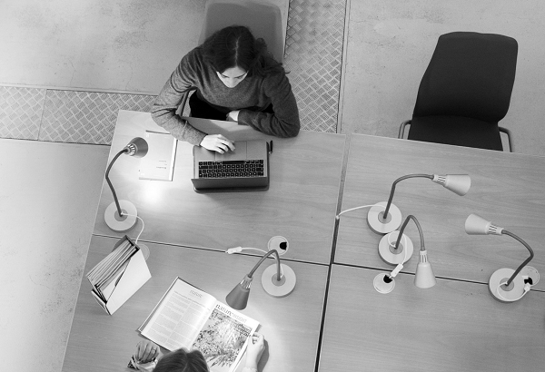 Two people studying in a library, seen from above. Photograph. 