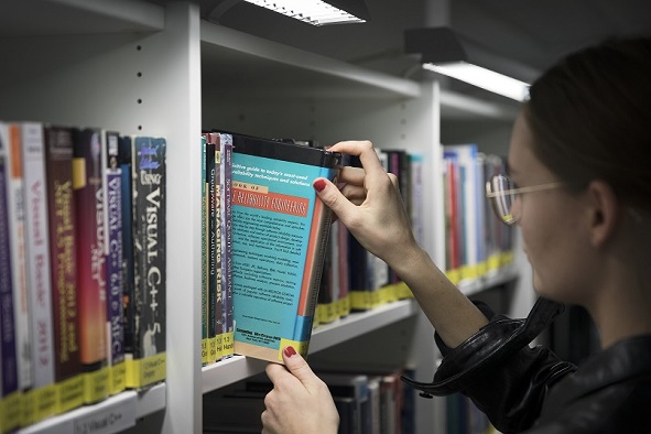 Photo. Person takes book from shelf.