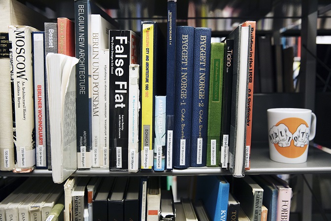 Biblioteksböcker och en kaffemugg ståendes i en bokhylla. Foto Johan Bävman.