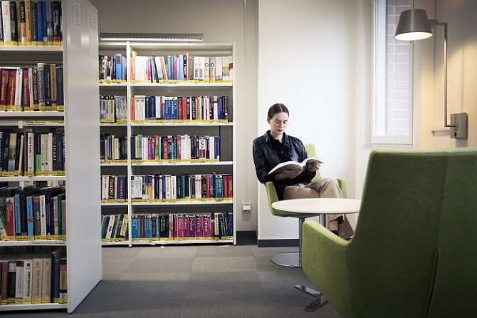 A person in an armchair reads in a library. Photo Johan Bävman.