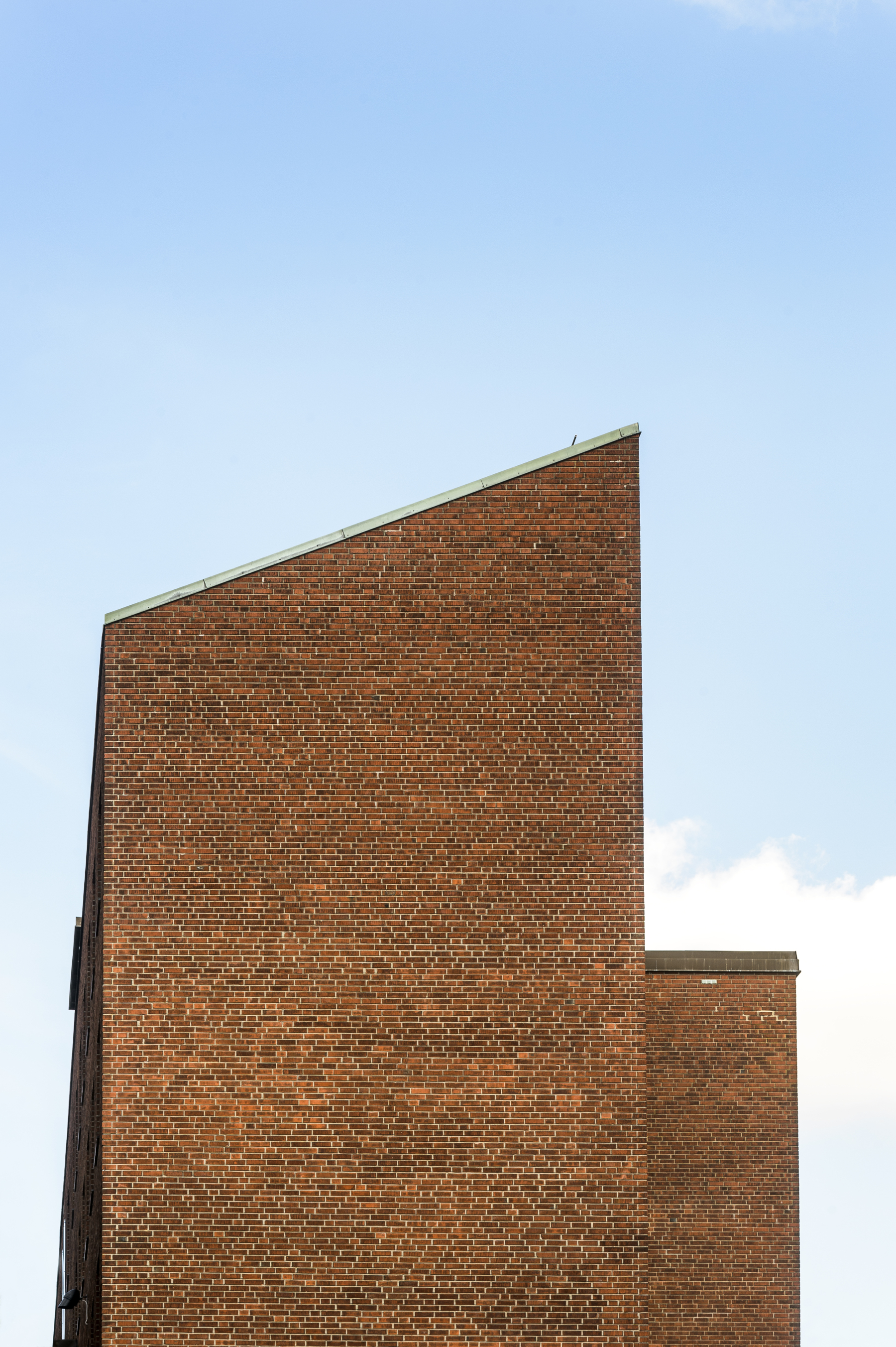 Spetsig gavel i rött tegel mot blå himmel. Typisk husgavel för LTH och dess arkitekt Klas Anshelm. Foto.