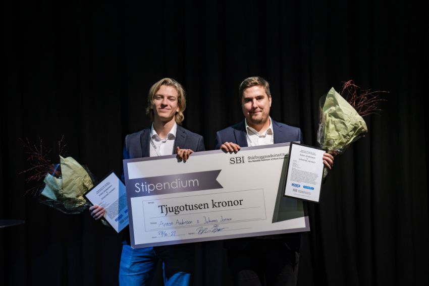 Två studenter tar emot en stor check.