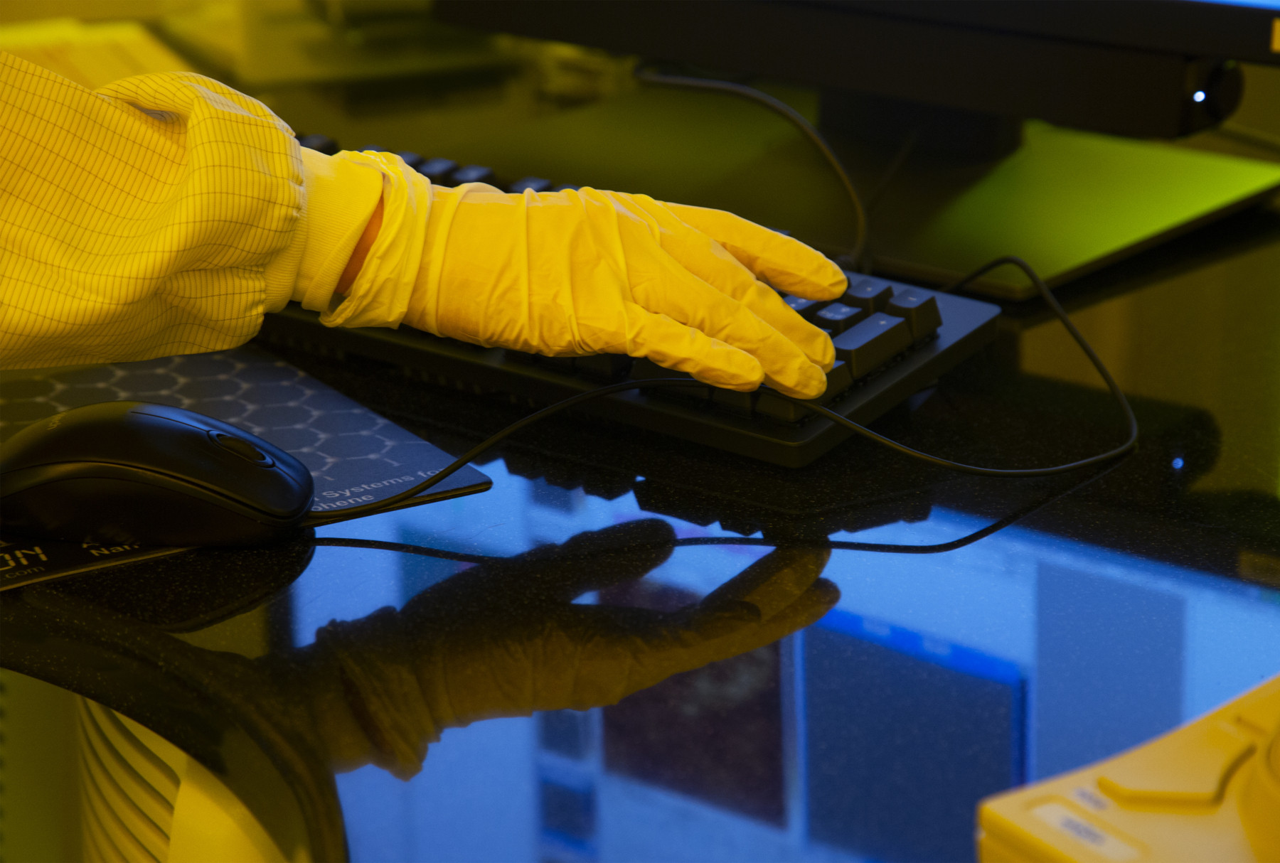 Researcher wearing a protective glove and using a desktop keyboard. Photo. 