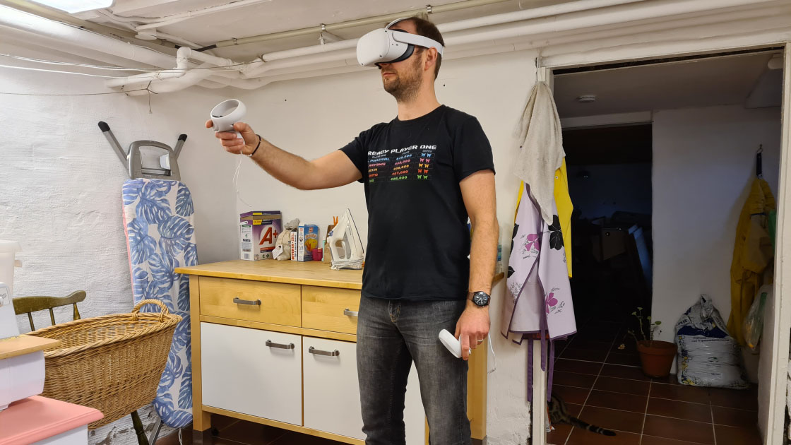 Photo of a man standing in a laundry room with a virtual reality head set on his head.