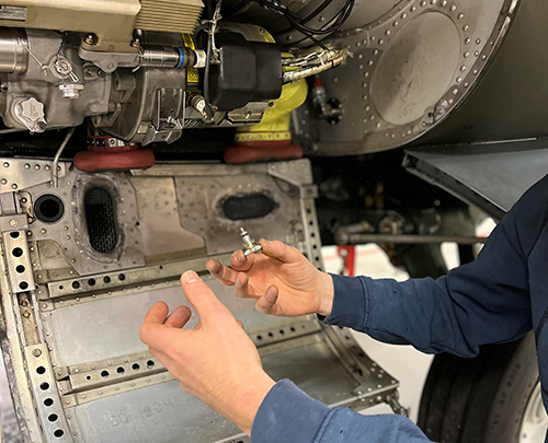 The inside of an engine with hands holding engineering parts. Photo.