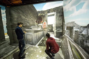 Two people standing in the virtual model of Pompeii. Photo.