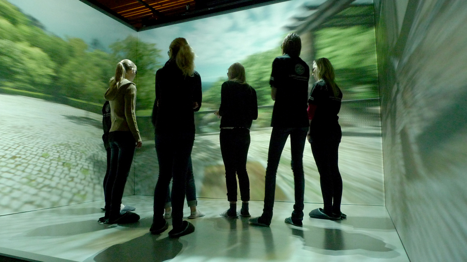 En grupp människor står inne i en virtuell cave. Foto.