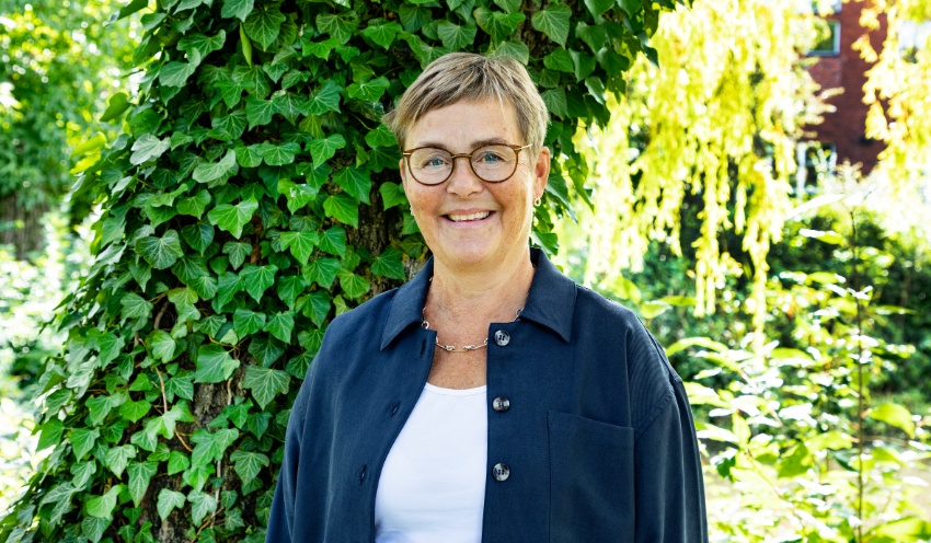 Annika Olsson in front of green leaves.