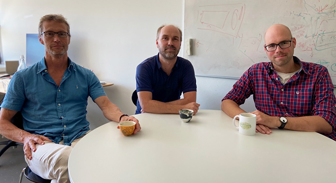Mikael Akke, Kresten Lindorff-Larsen and Eike-Christian Schulz are sitting around a table drinking coffee. Photo.