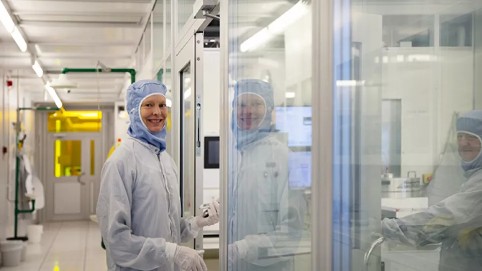Photo of a woman in the cleanroom laboratory, wearing protective clothes.