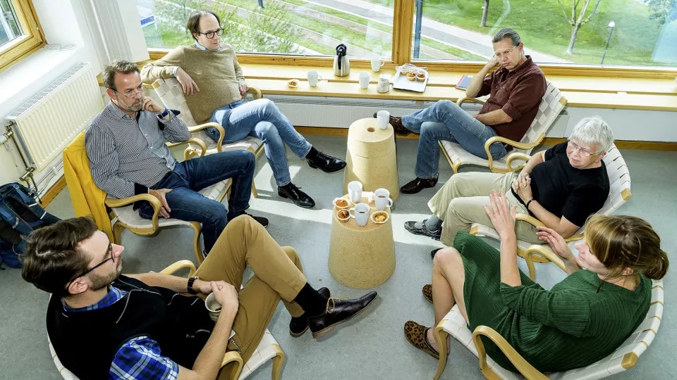 Sex forskare sitter runt ett bord och samtalar. Foto.