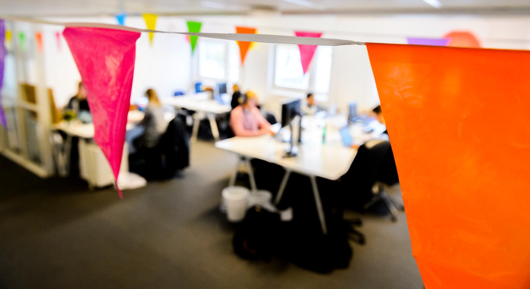 Young people working in an office, underneath colourful flags.