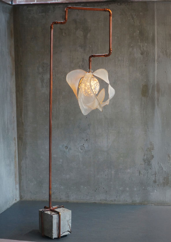 En lampa av betong och koppar, och med en vit skärm.