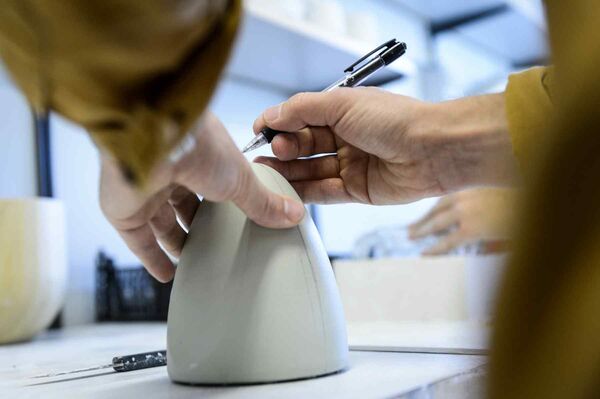 A person's hands are shown when working with a pencil and a plastic item. 