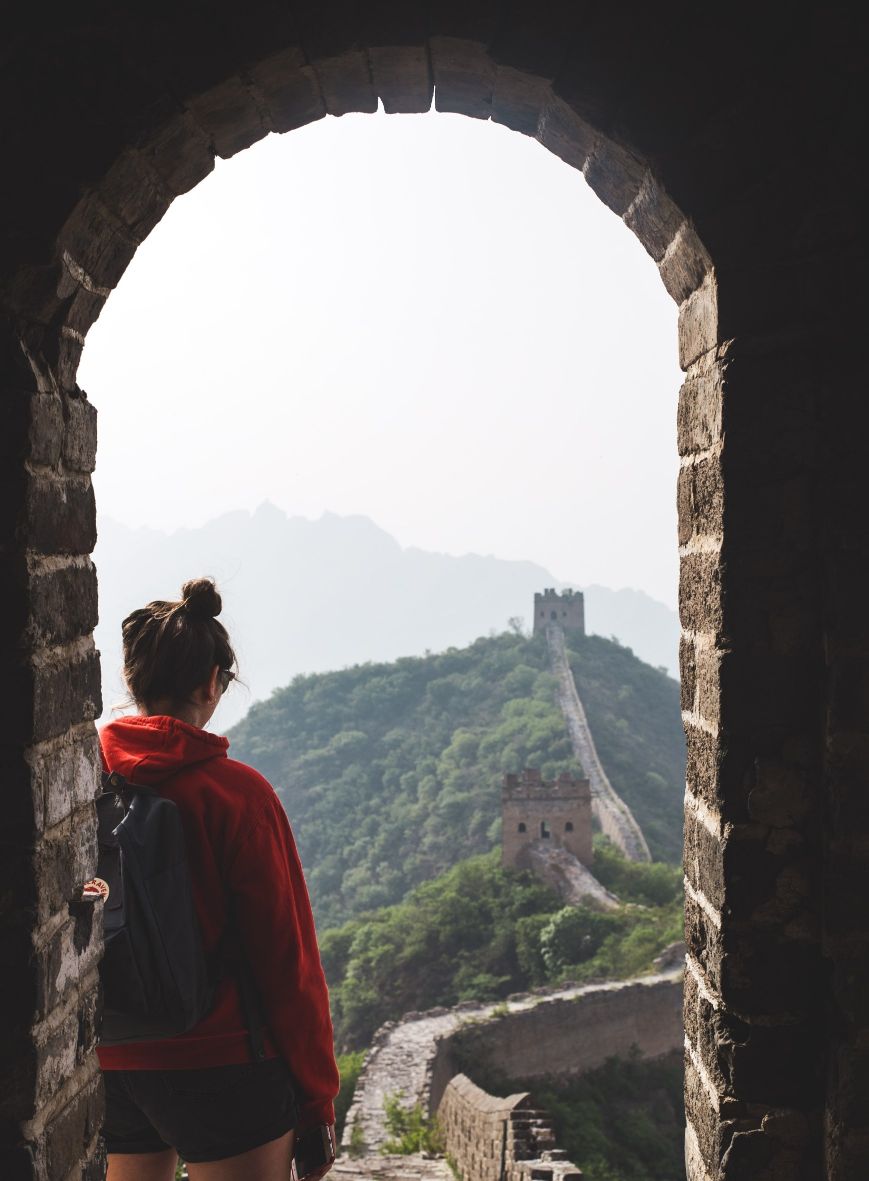 Kvinna i shorts ser ut över Kinesiska muren. Foto. 
